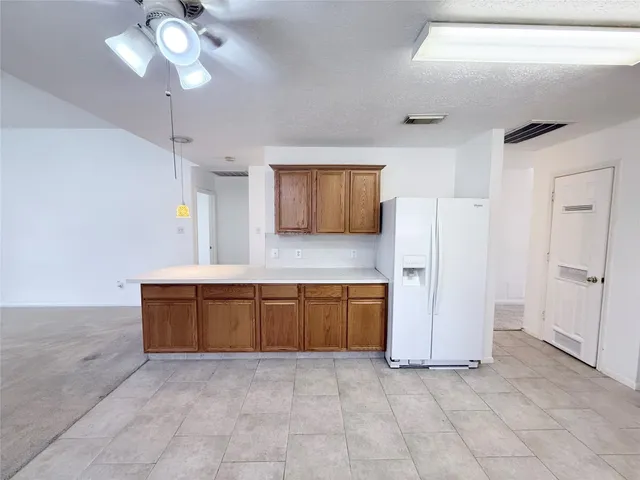 a kitchen with granite countertop a refrigerator a stove a microwave oven with cabinets and wooden floor