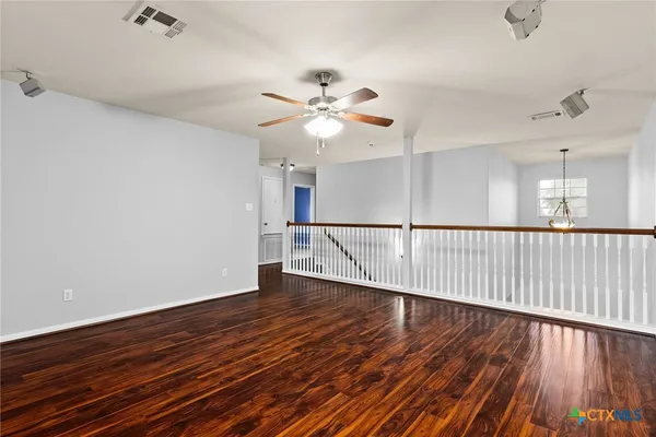 a view of a room with wooden floor ceiling fan and window
