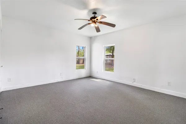 an empty room with windows and fan