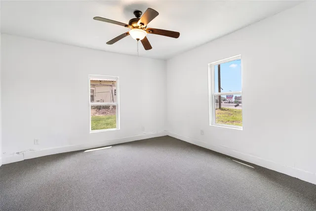 an empty room with windows and a ceiling fan