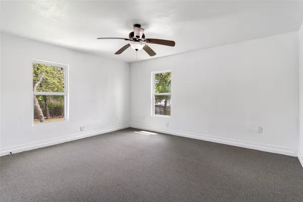 an empty room with windows and fan
