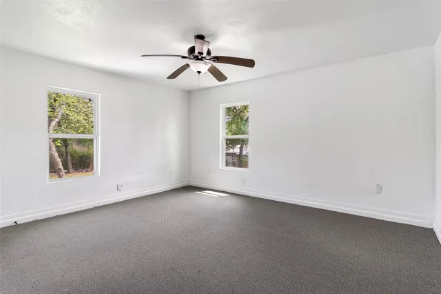an empty room with windows and fan