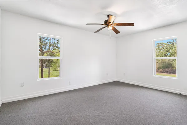 an empty room with windows and fan