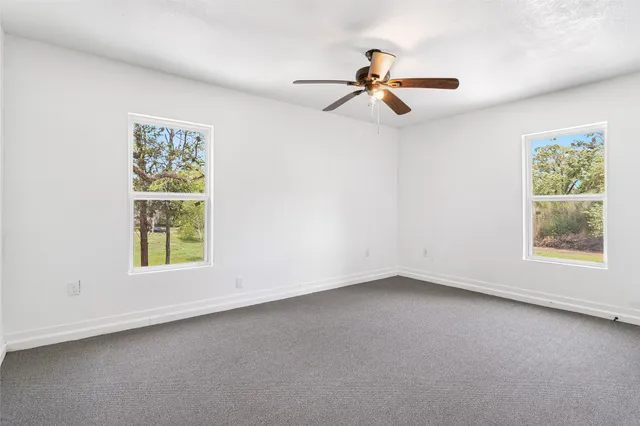 an empty room with windows and fan