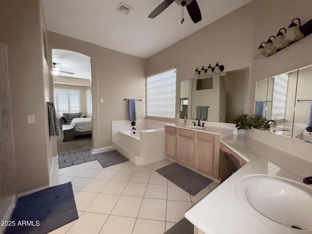 a large white bathroom with a double vanity sink a mirror and a bathtub