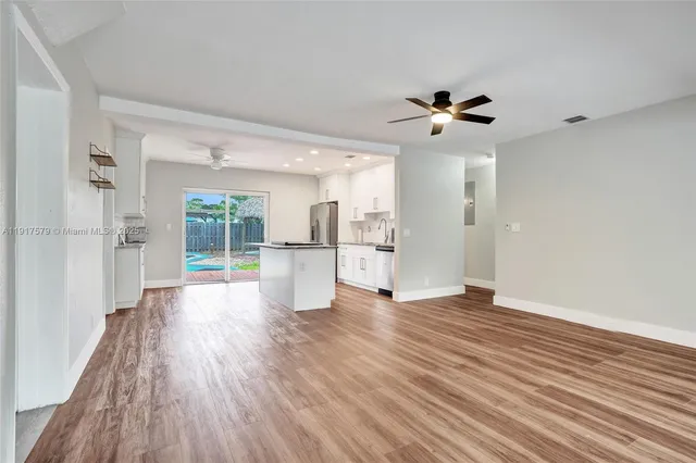 a view of a kitchen with a fridge wooden floor and a ceiling fan