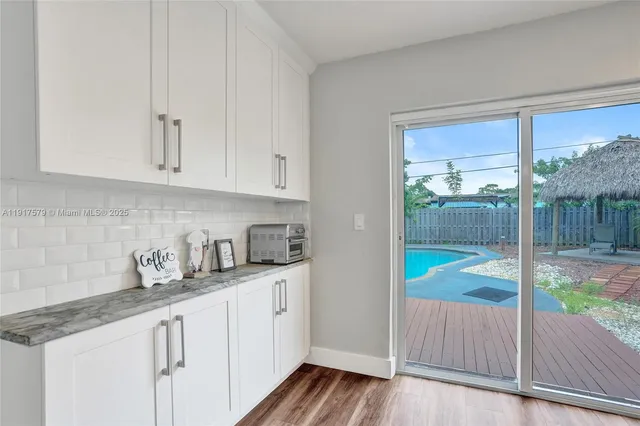 a kitchen with granite countertop a sink and white cabinets with wooden floor