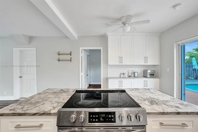 a kitchen with granite countertop a stove and white cabinets