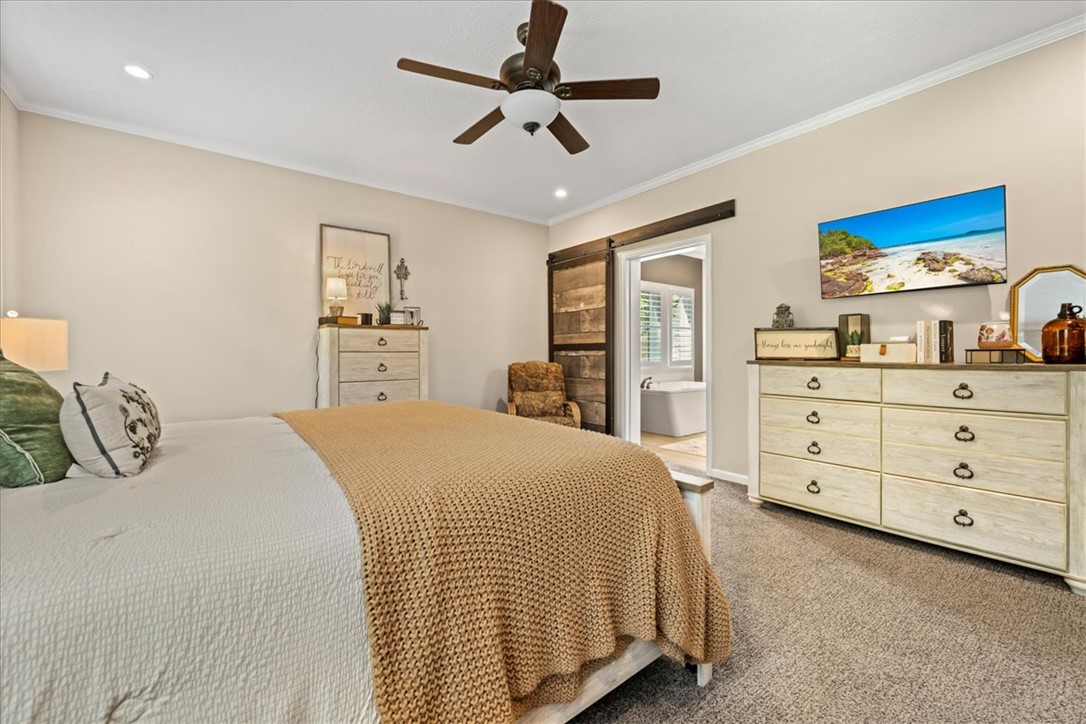 116 Parkview Road Iva, SC 29655 - Photo 22 of 44 A comforting bedroom features a ceiling fan, plush carpeting, and a rustic barn door leading to a private bath.