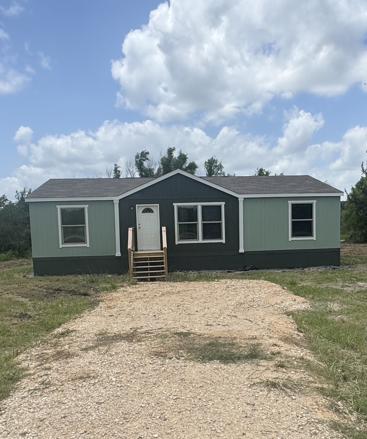 7855 Taylorsville Road Dale, TX 78616 - Photo 2 of 11 A quaint residence featuring a gravel driveway and partial wooden steps to the entry.