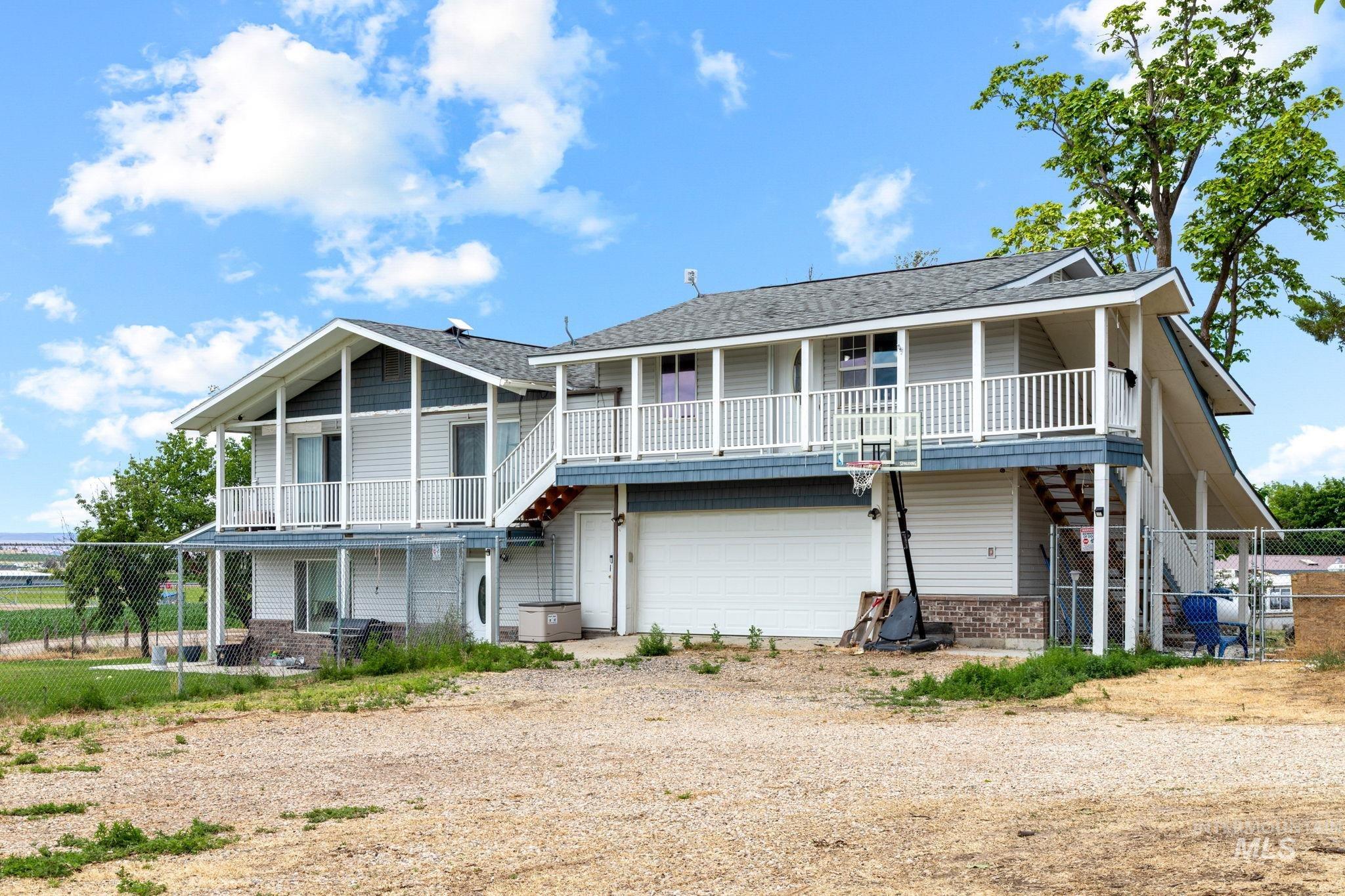 18338 Pride Lane Caldwell, ID 83607 - Photo 2 of 50 Multi-level exterior featuring white siding, grey shingle roofing, dual balconies with white railings, and a lower-level garage