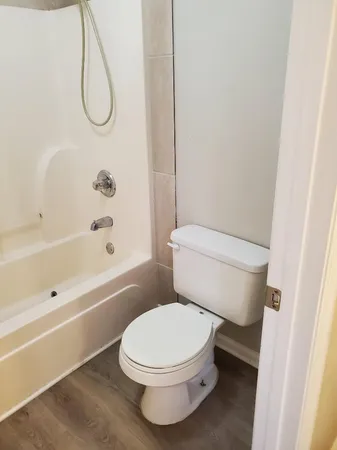 a white toilet sitting next to a bath tub and a shower