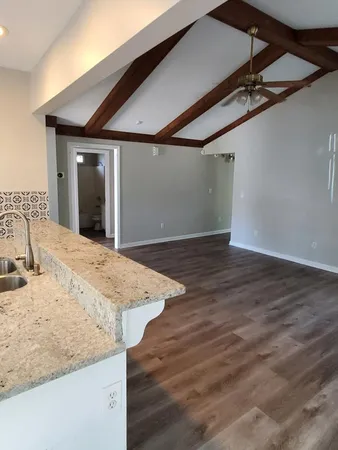 a view of a livingroom with wooden floor and kitchen space
