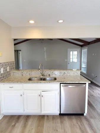 a kitchen with granite countertop white cabinets and a sink