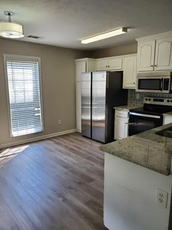 a kitchen with stainless steel appliances kitchen island granite countertop a refrigerator oven a sink with granite countertops and cabinets