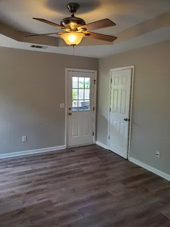 a view of empty room with wooden floor and fan