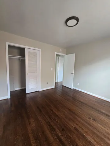 a view of an empty room with wooden floor and windows