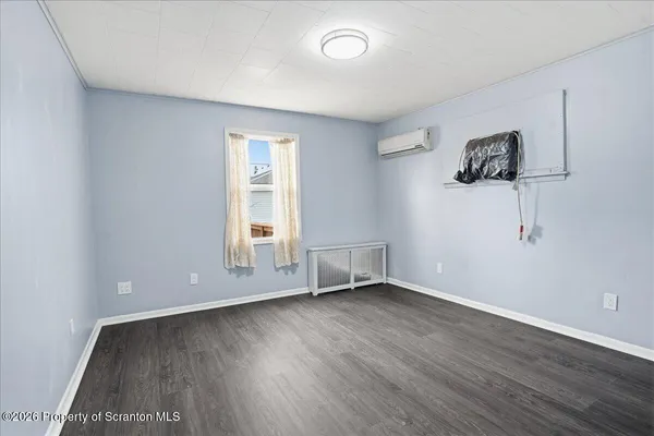 a view of an empty room with wooden floor and closet