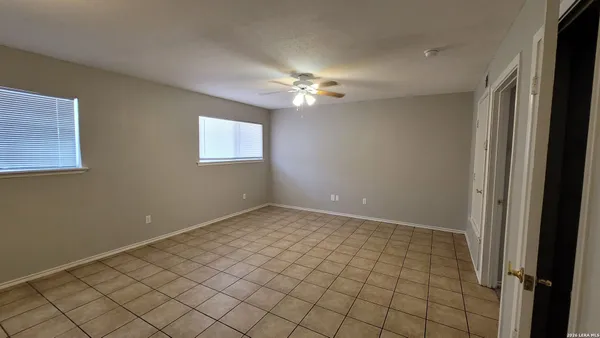 an empty room with windows and fan