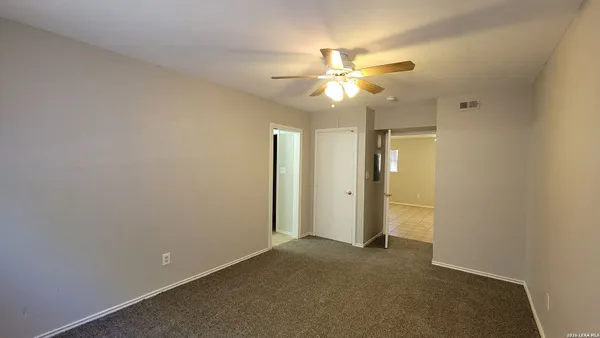 an empty room with a ceiling fan and a fan