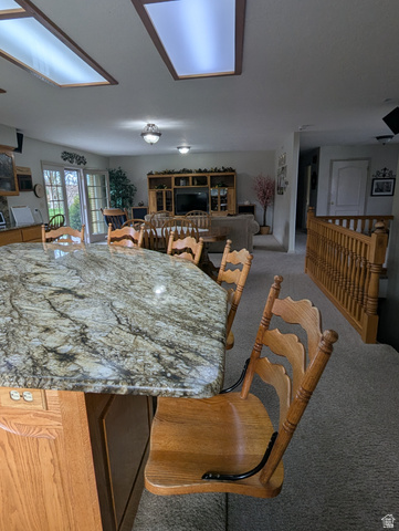 1040 West Mill Road Ferron, UT 84523 - Photo 17 of 117 Kitchen island featuring a polished stone countertop, wood cabinetry, and built-in seating