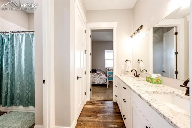 a spacious en suite bathroom with a granite countertop double vanity sink and mirror