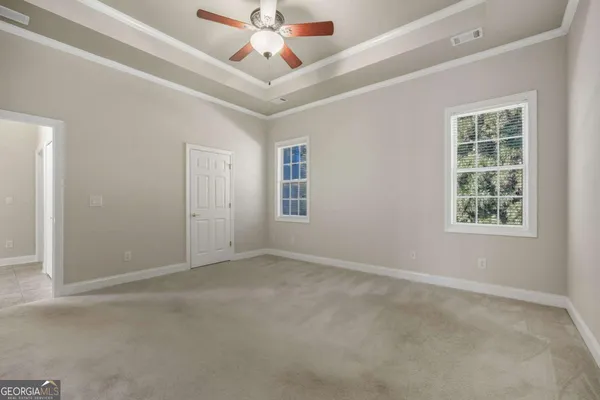 an empty room with windows and fan
