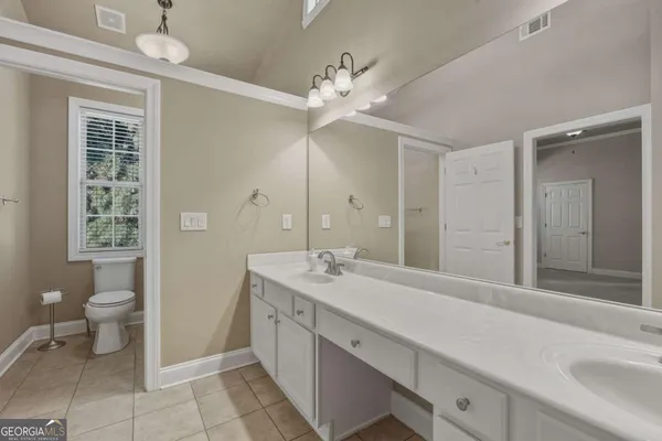 a spacious bathroom with a sink a toilet and a mirror