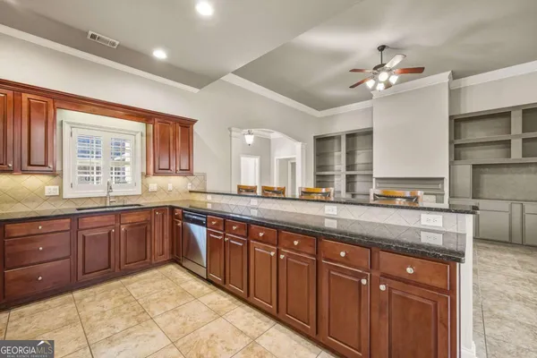 a large kitchen with kitchen island granite countertop a sink and dishwasher wooden cabinets with granite countertops
