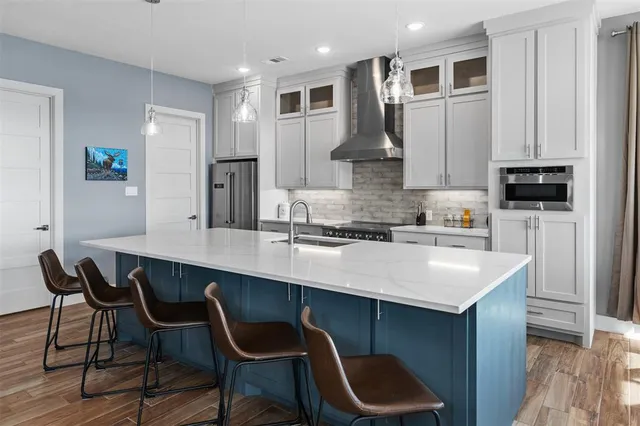 a kitchen with stainless steel appliances kitchen island granite countertop a table chairs in it and wooden floors