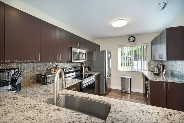 a kitchen with stainless steel appliances granite countertop a sink stove and refrigerator