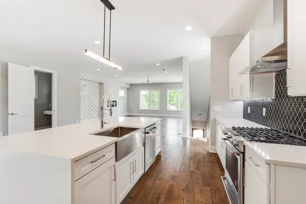 a kitchen with stainless steel appliances kitchen island granite countertop a sink a stove a dining table and chairs