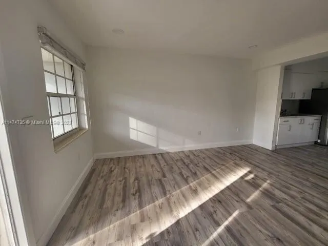 a view of empty room with wooden floor and window