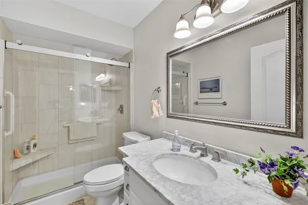 a bathroom with a granite countertop sink a toilet a shower and a mirror