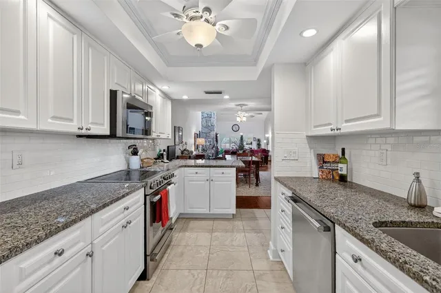 a kitchen with stainless steel appliances granite countertop a sink dishwasher stove and refrigerator with wooden cabinets