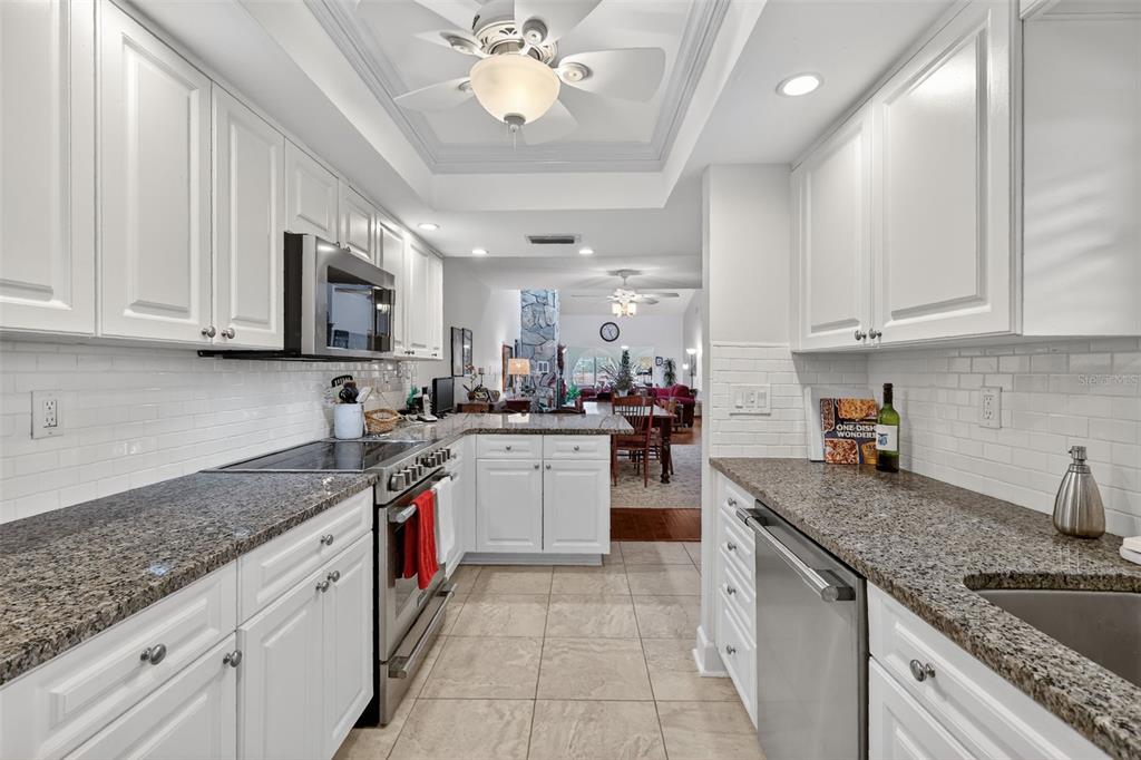 100 South Tremain Street, Unit F1 Mount Dora, FL 32757 - Photo 7 of 47 a kitchen with stainless steel appliances granite countertop a sink dishwasher stove and refrigerator with wooden cabinets