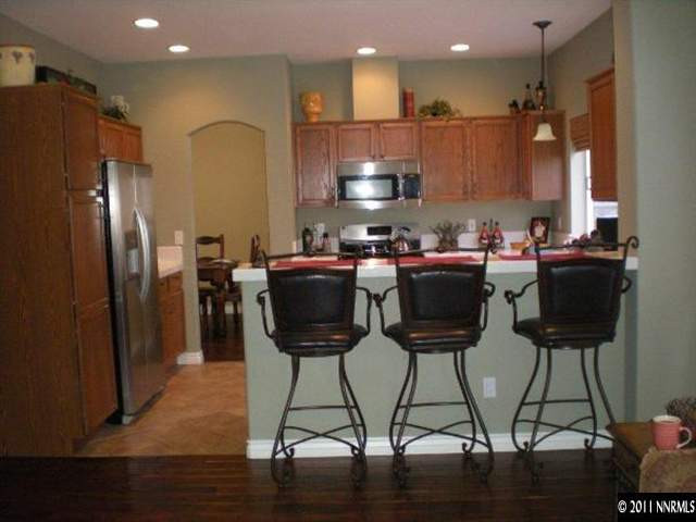 9779 Thunder Mountain Way Reno, NV 89521 - Photo 5 of 12 a kitchen with stainless steel appliances kitchen island granite countertop a table chairs and a refrigerator