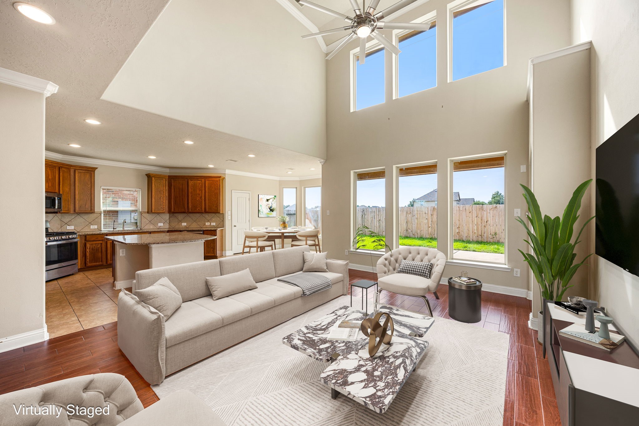 Open-concept family area featuring rich hardwood floors and expansive views into the kitchen and backyard.
