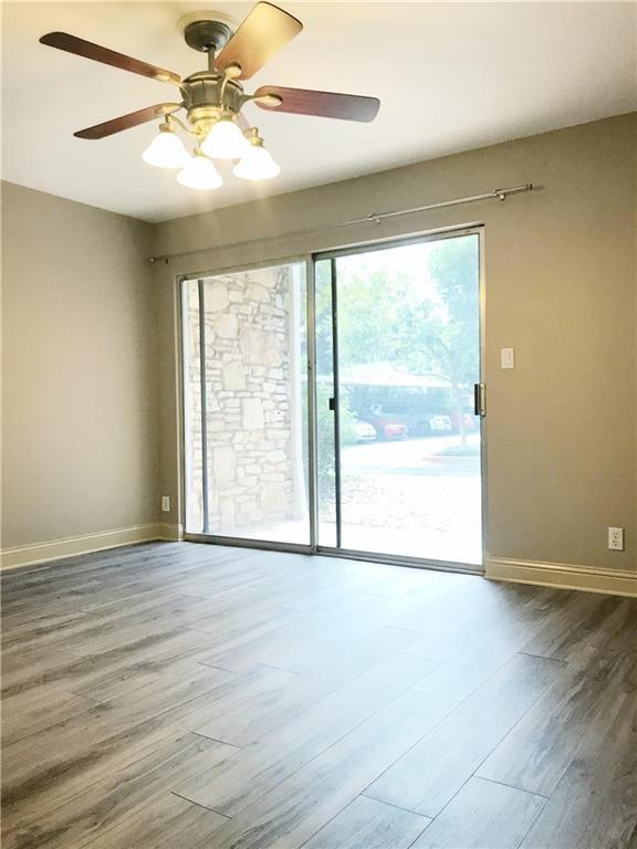 500 East Riverside Drive, Unit 154 Austin, TX 78704 - Photo 9 of 14 Spacious room featuring wood-finish flooring, a ceiling fan with integrated lighting, and a large sliding glass door