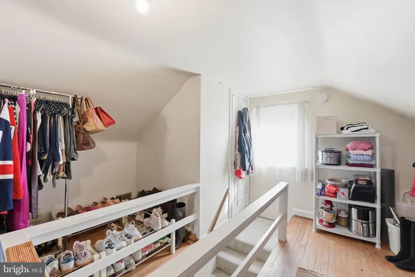 a walk in closet with clothes and shoes