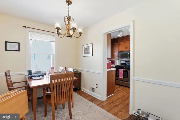 a dining room with wooden floor a chandelier a wooden table and chairs
