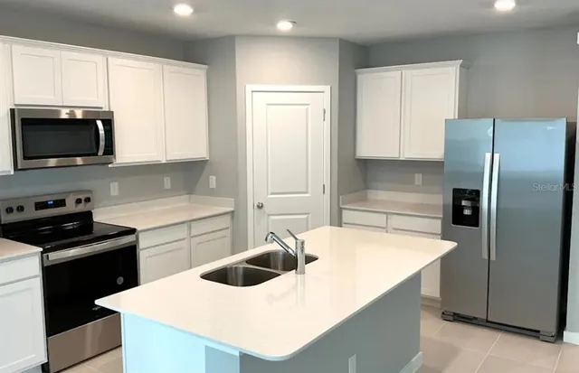 a kitchen with stainless steel appliances a stove a sink a microwave and refrigerator