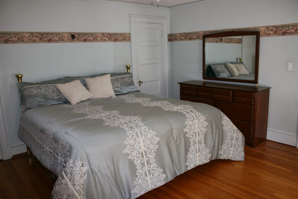 104 Shefford Street Springfield, MA 01107 - Photo 14 of 18 a bed sitting in a bedroom next to a cabinet with mirror