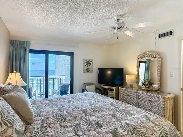 a bedroom with a bed a chandelier and a flat screen tv
