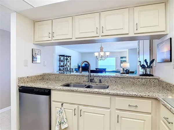 a kitchen with stainless steel appliances granite countertop a refrigerator a stove top oven a sink and dishwasher with wooden floor