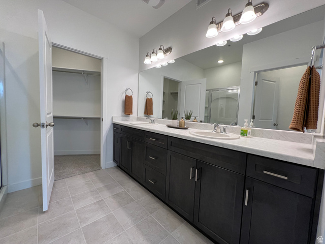718 West Blue Magic Lane, Unit S201 Midvale, UT 84047 - Photo 10 of 18 Bathroom featuring a stall shower, double vanity, and a spacious closet