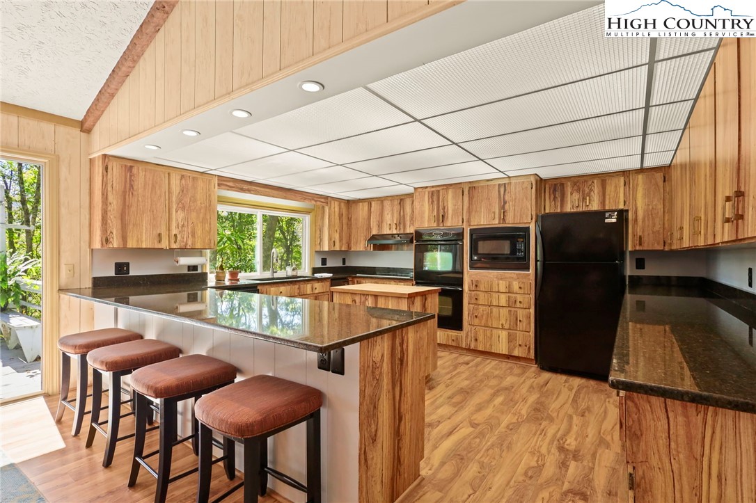 202 Cliffside Lane Seven Devils, NC 28604 - Photo 11 of 46 a kitchen with stainless steel appliances kitchen island granite countertop counter top space a refrigerator and cabinets