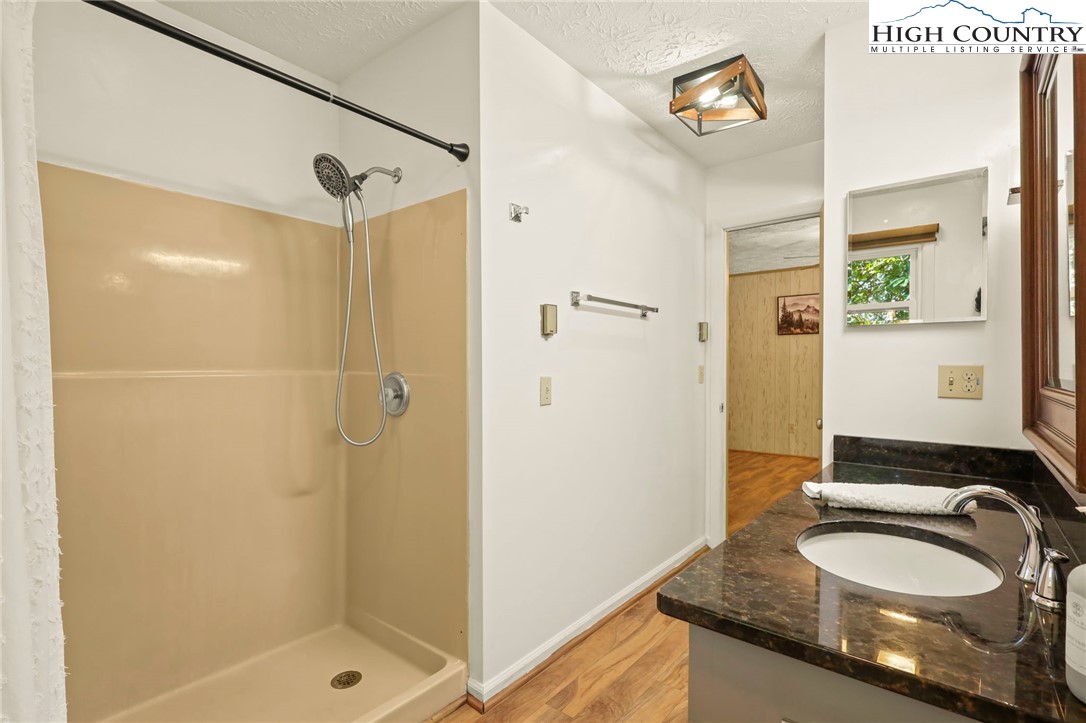 202 Cliffside Lane Seven Devils, NC 28604 - Photo 23 of 46 a bathroom with a granite countertop sink a mirror and a shower