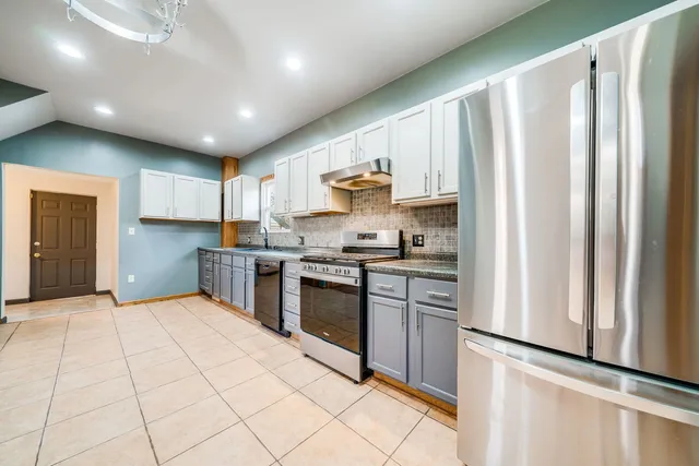 a kitchen with stainless steel appliances granite countertop a refrigerator and a stove top oven