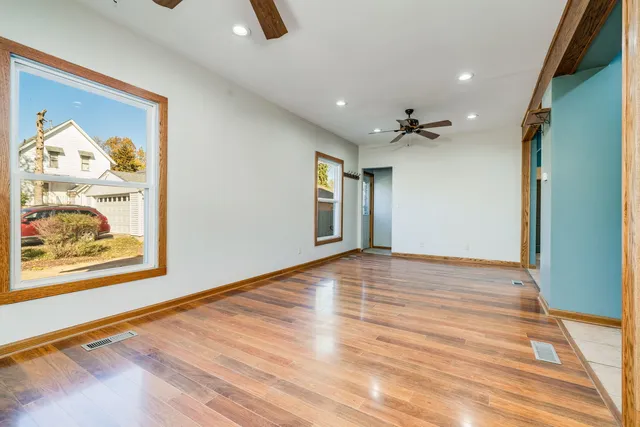 a view of an empty room with wooden floor and a window